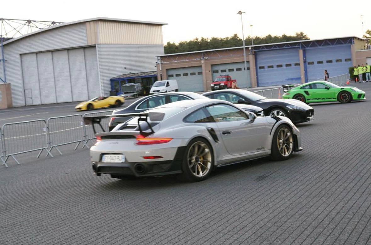 Performance cars moving through a circuit paddock